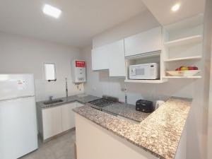 a kitchen with white cabinets and a counter top at Depto Moreno in Rosario +4 photos