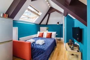 Schlafzimmer mit blauen Wänden und einem Bett mit orangefarbenen Stühlen in der Unterkunft Sunny Loft in Center of London in London