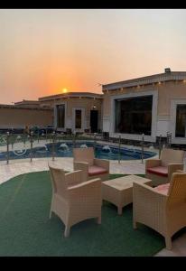 a patio with chairs and a pool with the sunset at منتجع زهرة سلسبيل بالمدينه المنورة in Al Madinah