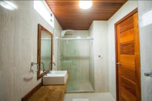 y baño con ducha, lavabo y espejo. en Pousada Jardim Cambuí Beach, en Itacimirim