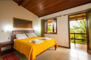 1 dormitorio con 1 cama con manta amarilla en Pousada Jardim Cambuí Beach, en Itacimirim
