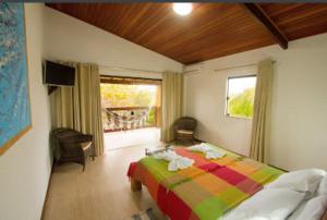 a bedroom with a colorful bed and a window at Pousada Jardim Cambuí Beach in Itacimirim