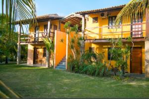 a yellow house with a yard in front of it at Pousada Jardim Cambuí Beach in Itacimirim