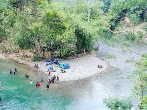 a group of people on a beach in a river at Bukit Lawang Glamping & Jungle Trekking in Bukit Lawang