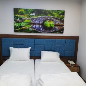 two beds in a room with a painting on the wall at seyir yeri otel in Trabzon