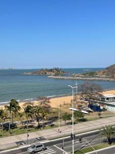 Blick auf den Strand und eine Straße mit Autos in der Unterkunft Flat PRAIA Home Experience Dante Michelini in Vitória