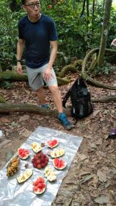 Ein Mann steht neben einem Tisch mit Obst drauf. in der Unterkunft Bukit Lawang Glamping & Jungle Trekking in Bukit Lawang