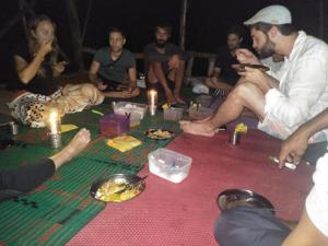 Eine Gruppe von Menschen, die an einem Tisch sitzen und Essen essen. in der Unterkunft Bukit Lawang Glamping & Jungle Trekking in Bukit Lawang