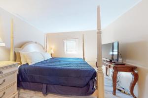 1 dormitorio con 1 cama con edredón azul y TV en Tuftonboro Retreat, en Tuftonboro