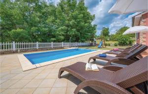 a swimming pool with chairs and a table with an umbrella at Nice Home In Vinez With 3 Bedrooms, Wifi And Outdoor Swimming Pool in Vinež