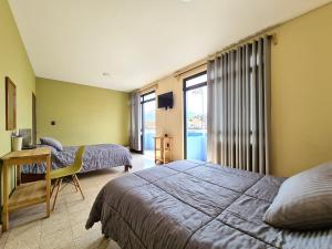 a bedroom with two beds and a desk and a window at Hotel Galaxia in Oaxaca City