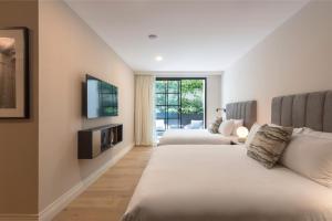 メキシコシティにあるThe Amsterdam-Luxury Plus by Viadoraのベッド2台とテレビが備わるホテルルームです。