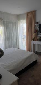 una camera da letto con un letto con lenzuola bianche e una finestra di D&H a Năvodari