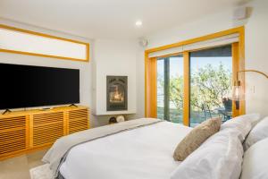 a bedroom with a large white bed and a tv at Downtown Contemporary Coastal Condo in Anchorage