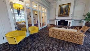 a living room with yellow chairs and a fireplace at Bournemouth Carlton Hotel, BW Signature Collection in Bournemouth