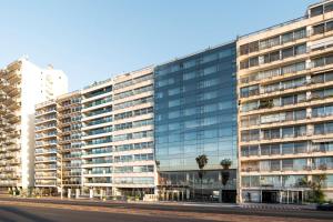 ein großes Gebäude mit Glasfenstern auf einer Straße in der Unterkunft Hotel Costanero MGallery - ACCOR in Montevideo