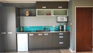 a kitchen with gray cabinets and a microwave at Heart of Kerikeri - The Studio in Kerikeri