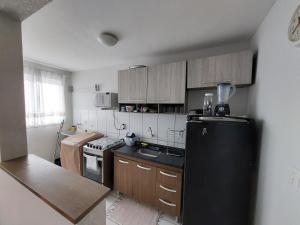 eine Küche mit einem schwarzen Kühlschrank und Holzschränken in der Unterkunft Apartamento próx ao centro Londrina in Londrina