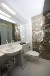 a bathroom with a sink and a toilet and a mirror at AR Suites Fontana Bay - Kalyani Nagar in Pune