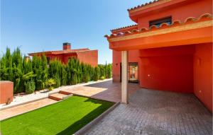 an orange house with a green lawn in the courtyard at Beautiful Home In Caravaca De La Cruz With Kitchen in Caravaca de la Cruz
