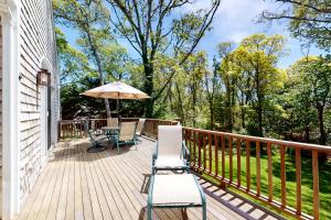 a wooden deck with chairs and an umbrella at Spinnaker Trail in Orleans