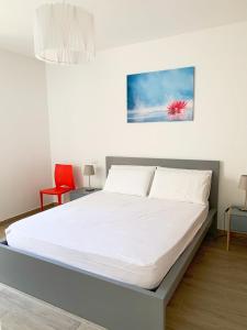 Cama blanca en habitación con silla roja en Conero-30 mt dal Mare, Corte e Spiaggia di sabbia-Stella en Porto Potenza Picena