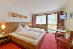 ein Hotelzimmer mit einem Bett, einem Schreibtisch und einem Tisch in der Unterkunft Hotel Sonnblick in Wald am Arlberg