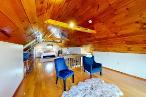 a living room with wooden ceilings and blue chairs at Stowe Hideout Unit 1 in Stowe