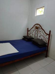 een slaapkamer met een bed met blauwe lakens en een raam bij Homestay Srikandi in Garut