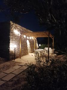 un patio di notte con un edificio in pietra con luci di Liama sull'Aia a Marina di Pescoluse