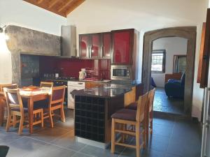 a kitchen with red cabinets and a table and chairs at Casa do Outeiro - AL in Praia da Vitória