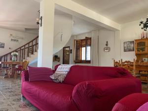un divano rosso in un soggiorno con scala di Villa Persefone - Splendida villa con giardino a Ficarazzi