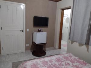 een slaapkamer met een flatscreen-tv aan de muur bij Casa do Trem Suítes in Campos do Jordão