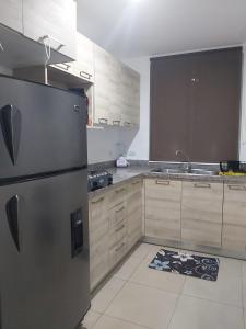 a kitchen with a stainless steel refrigerator and wooden cabinets at Casa en Playa Privada - A pocos minutos de General Villamil Playas in Posorja