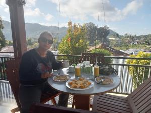 Eine Frau, die an einem Tisch mit einem Teller Essen sitzt. in der Unterkunft Mahakali in Kelimutu