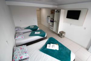 a small room with two beds and a tv at Pousada Graff in Penha