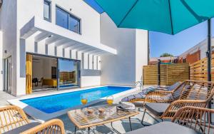 un patio con piscina, sillas y sombrilla en Villa RougeMarin - Marin with private pool en Medulin