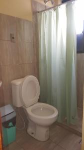 a bathroom with a toilet and a shower curtain at Concordia - Hospedaje in Cochabamba