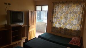 um quarto com uma televisão, uma cama e uma janela em Concordia - Hospedaje em Cochabamba
