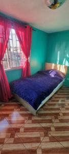 1 dormitorio con 1 cama con sábanas moradas y cortinas rojas en Casa Enea Pudahuel, en Santiago