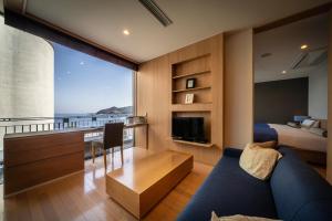 a living room with a blue couch and a bedroom at Auberge Fontaine Bleau Atami in Atami