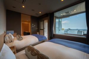 a bedroom with two beds and a large window at Auberge Fontaine Bleau Atami in Atami