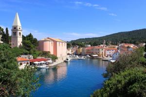 a river with boats in a town with a church at Apartments with a parking space Veli Losinj, Losinj - 8060 in Veli Lošinj