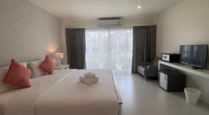 un osito de peluche sentado en una cama en una habitación de hotel en Shunli Hotel - SHA Extra Plus en Phuket