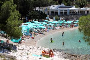 a group of people on a beach with blue umbrellas at Apartments by the sea Mali Losinj (Losinj) - 8001 in Mali Lošinj