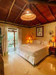 a bedroom with a large bed and a chandelier at Mata N'ativa Pousada in Trancoso