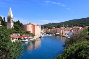 a river with boats in a town with a church at Apartments by the sea Veli Losinj, Losinj - 7959 in Veli Lošinj