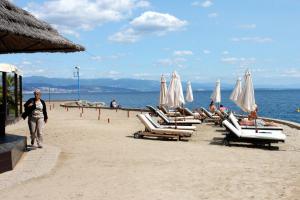 a beach with chaise lounges and umbrellas at Apartments with a parking space Opatija - 3436 in Opatija