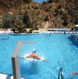 a person swimming in a swimming pool with a mountain at Balneario de Archena - Hotel León in Archena