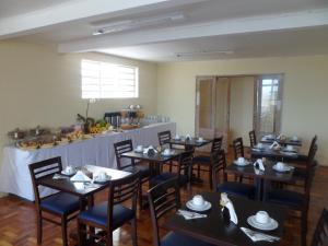 a dining room with tables and chairs and a counter at Hotel Embaixador in Cruzeiro